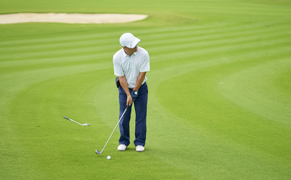 Asian golfer standing in course aiming