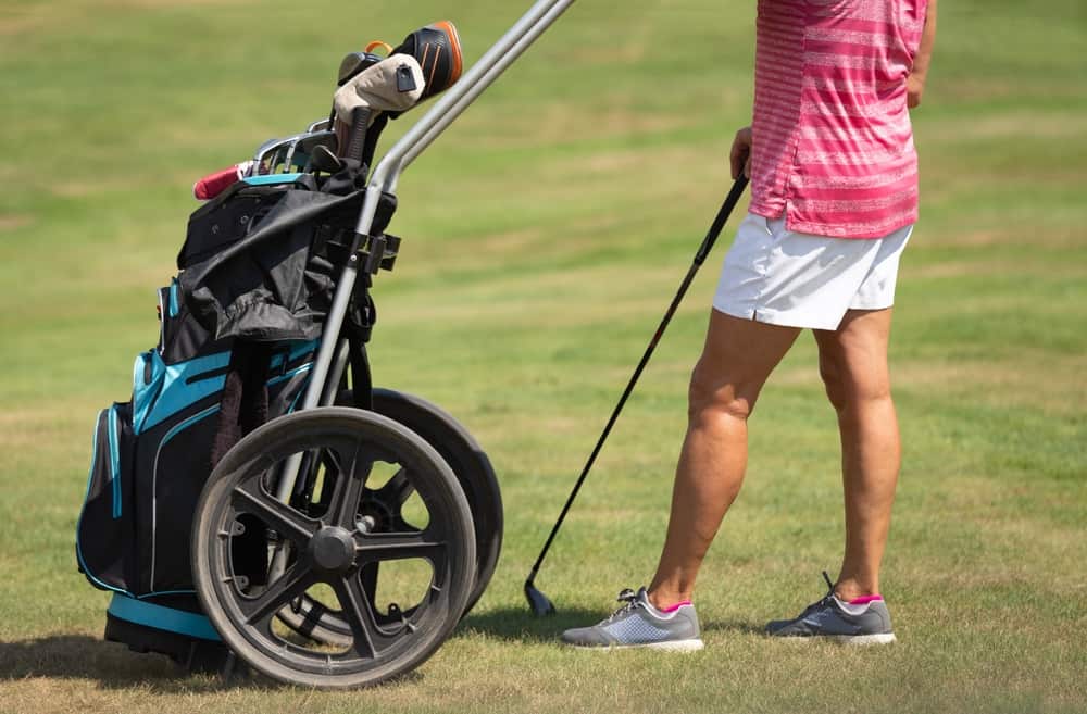 Close-up on golfer and golf push cart