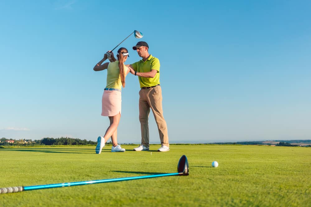 Golf instructor teaching a young woman to swing