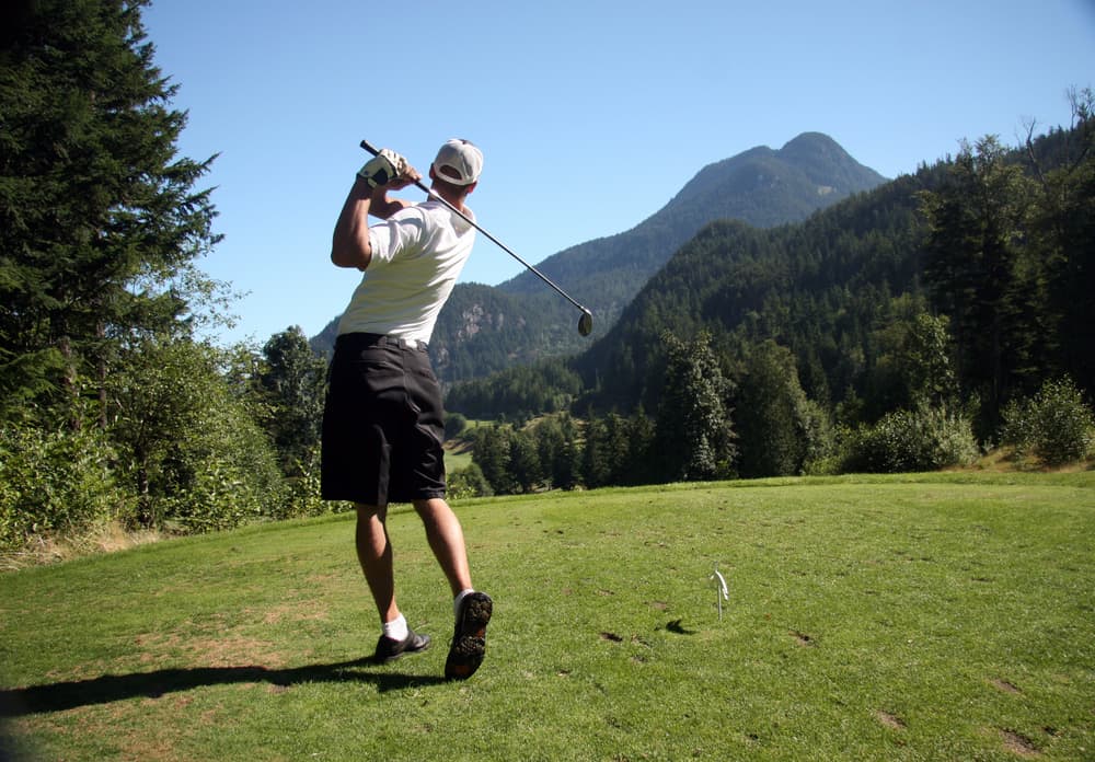 Golfer tees off on mountain course