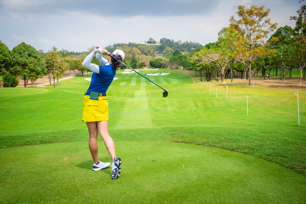 golfer is teeing off golf ball by golf club