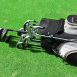 Golf bag with clubs on green field