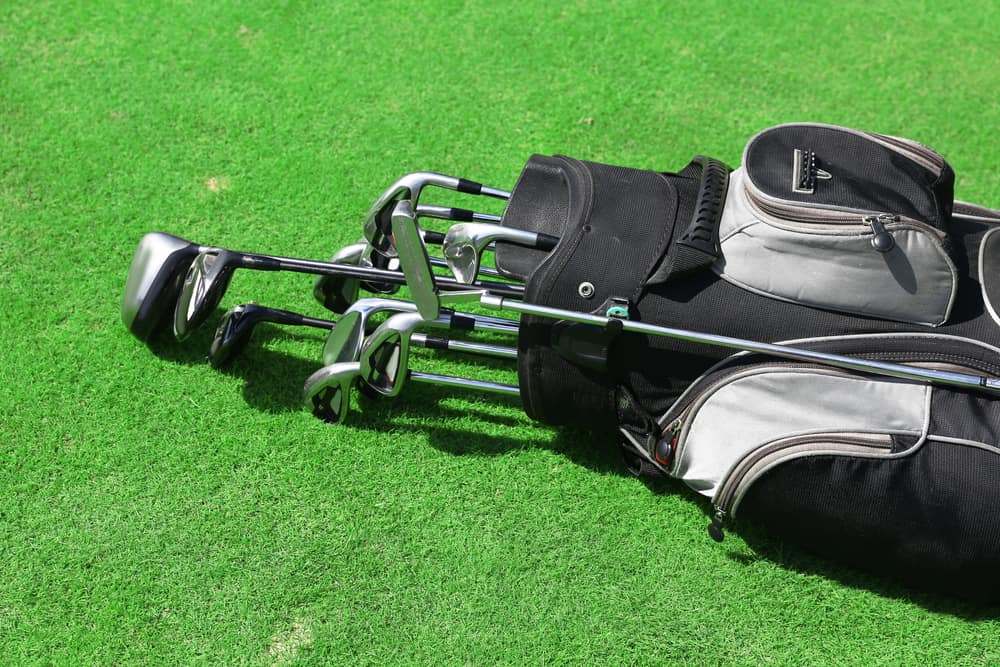 Golf bag with clubs on green field