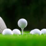 Golf balls and golf club on green grass