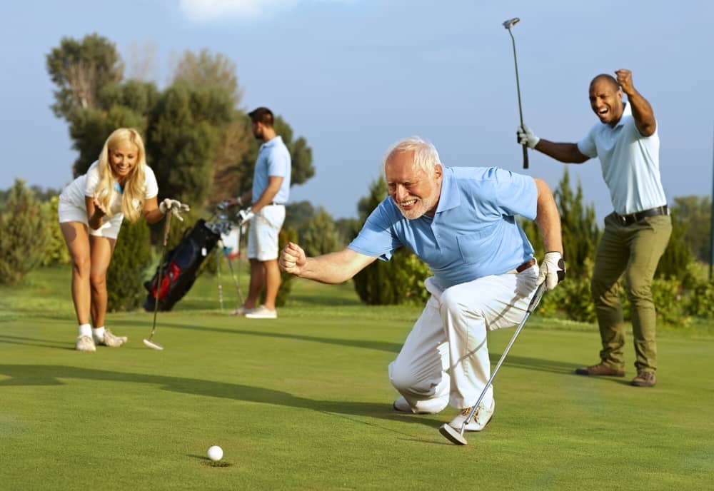 Happy senior golfer following golf ball to hole after putting