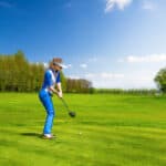 Woman golf player hitting by iron from fairway