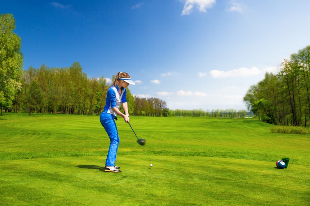 Woman golf player hitting by iron from fairway