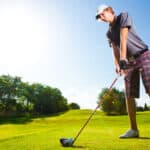 golf player teeing off golf ball from tee box