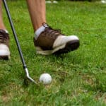 Close-up of man's feet with golf shoes and out of focus golf club and ball