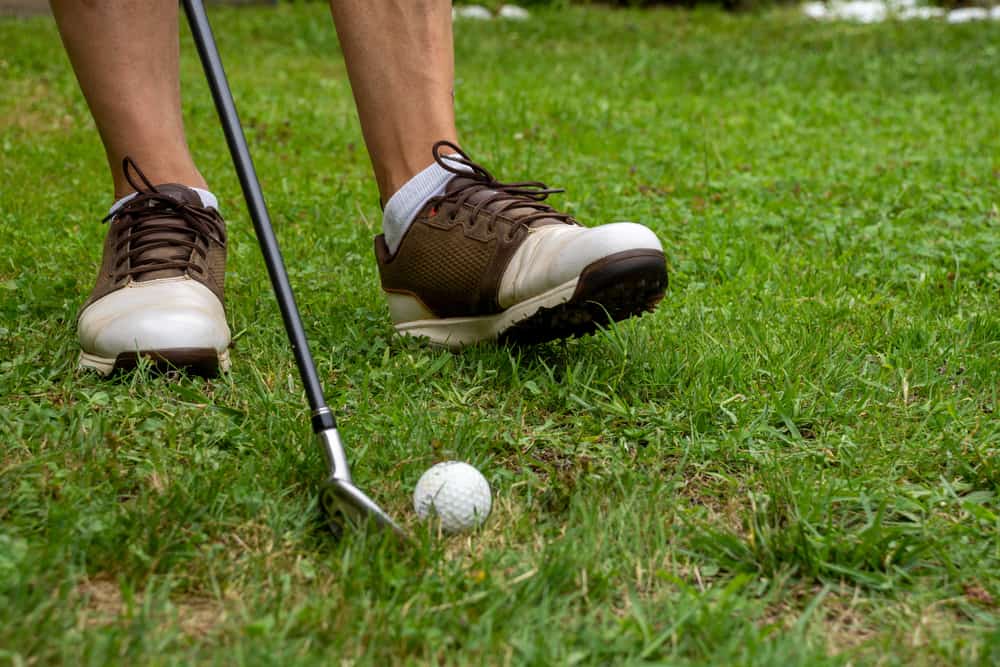 Close-up of man's feet with golf shoes and out of focus golf club and ball