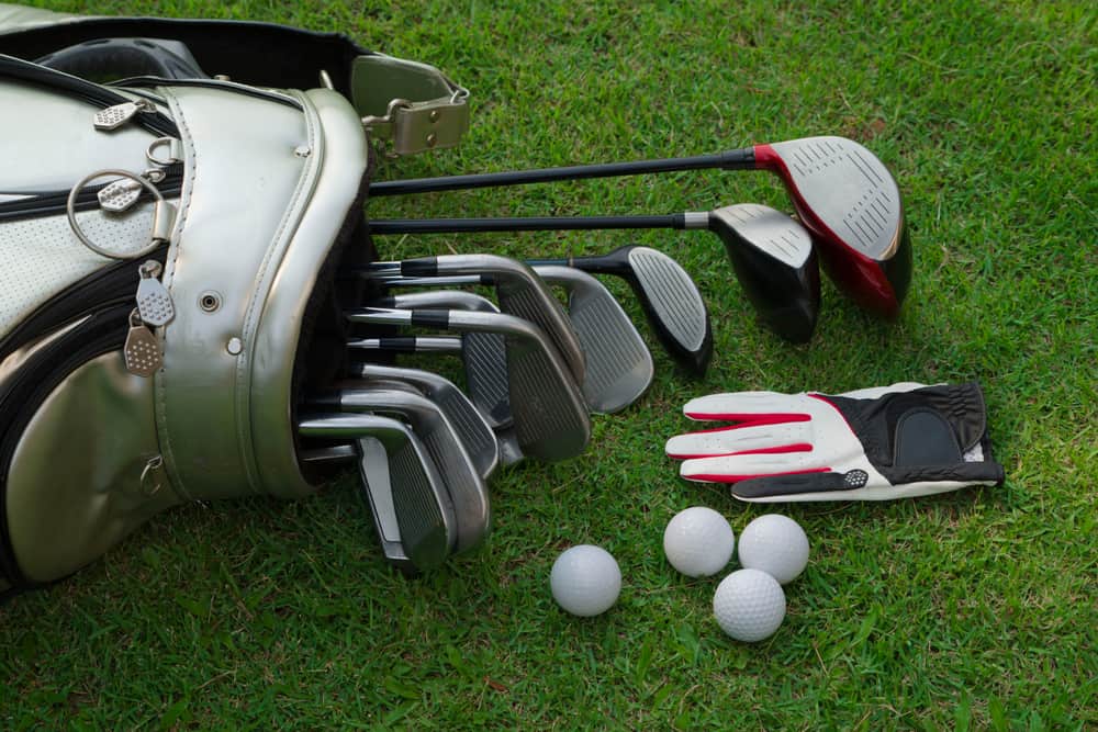 Closeup old golf bags on green. Set of golf clubs over green field background.