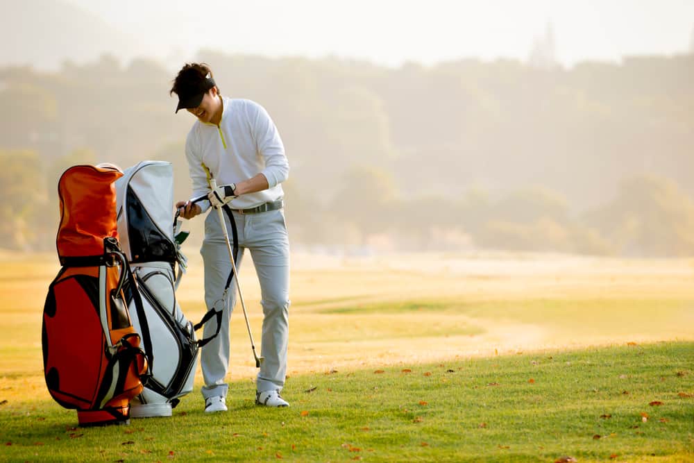 Happy Asian man golfer holding golf bag at golf course , Golfer playing golf