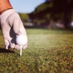 Close up of golf players hand placing ball on tee