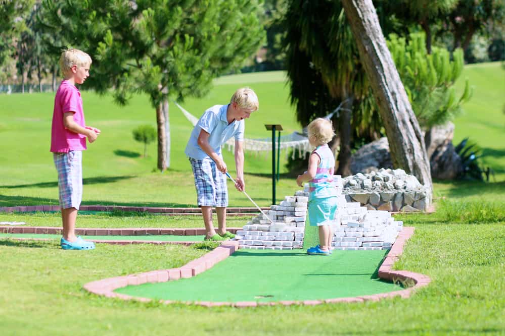 Group of kids playing mini golf outdoors