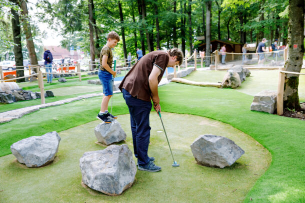 School kid boy playing mini golf with father