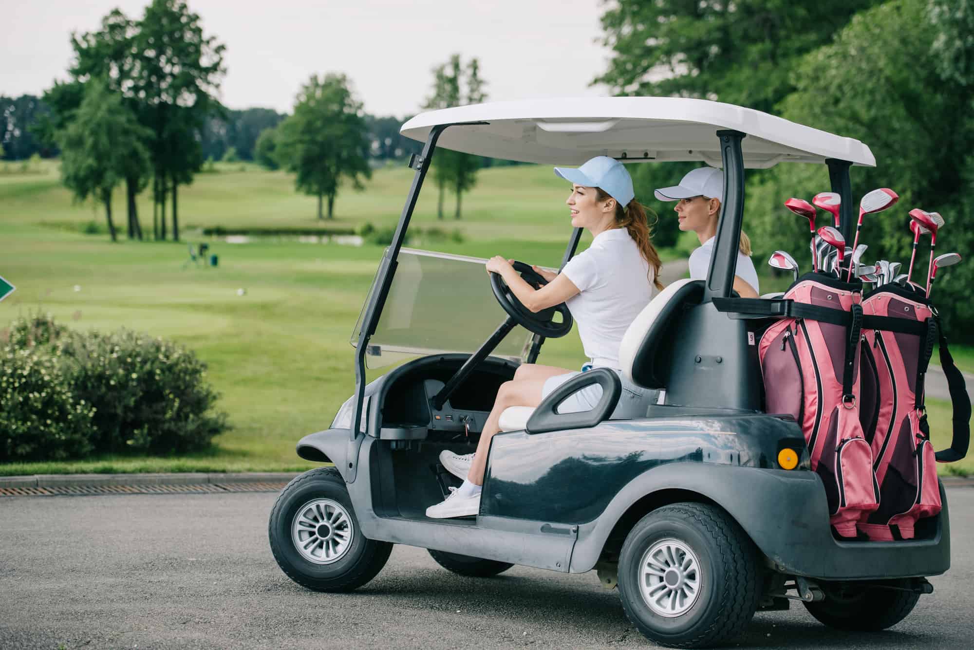  New Remove BG Cart Save Share Sample New Side view of female golfers in caps riding golf cart